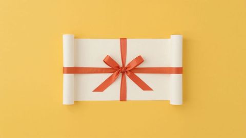 Elegantly wrapped scroll with red satin ribbon on yellow background