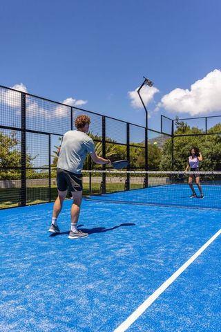 Man and woman playing padel on vibrant blue court under clear sunny sky