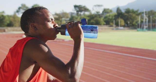 Thoughtful african american male athlete drinking water at empty stadium - Download Free Stock Photos Pikwizard.com