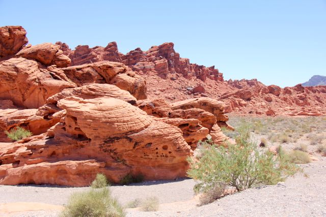 This photo features unique red rock formations in a desert landscape under a clear blue sky. Ideal for travel blogs, geological research articles, and adventure tourism marketing. Perfect visual for illustrating arid environments and natural beauty of desert regions.