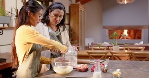 Mother and daughter bonding in cozy kitchen mixing dough