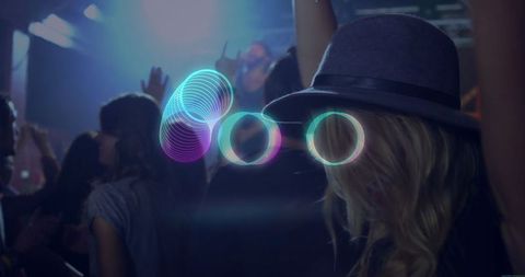 Woman in Grey Fedora Interacting with Neon Rings at Concert