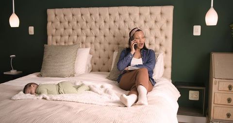 Mother Relaxing with Baby on Bed Using Smartphone
