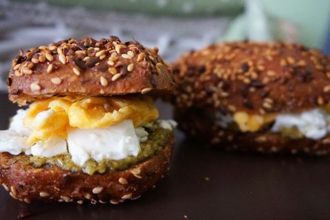 Toasted sesame bagel sandwich with scrambled eggs, cream cheese and pesto spread