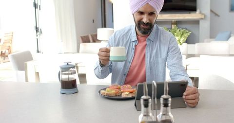 Man in Turban Enjoying Breakfast and Using Tablet at Home