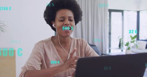 Woman conducting virtual meeting on laptop with wired earbuds and floating currency data