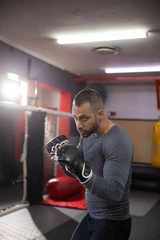 Indian man training mma in gym wearing compression top and fingerless gloves, sparring focus