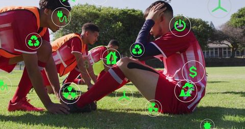 Soccer player sitting holding head after injury during team training on sunlit field