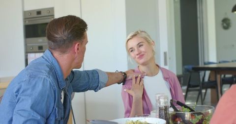 Couple sharing playful moment at kitchen table during casual meal in bright modern home