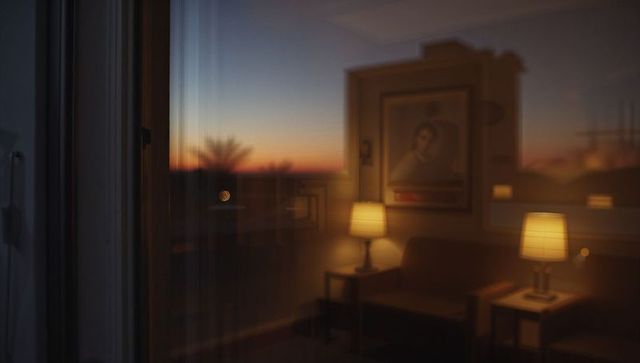 Sunset reflecting living room glass with warm lamps, framed portrait and moody bokeh