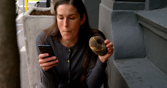 Woman with Donut Checking Smartphone Outdoors - Download Free Stock Images Pikwizard.com