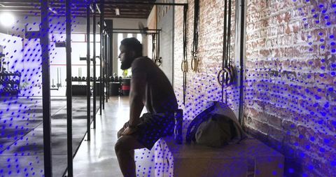 Male athlete resting between crossfit sets in industrial gym with exposed brick wall