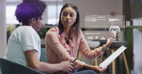 Woman Presenting Augmented Reality Data to Coworker in Modern Office Lounge