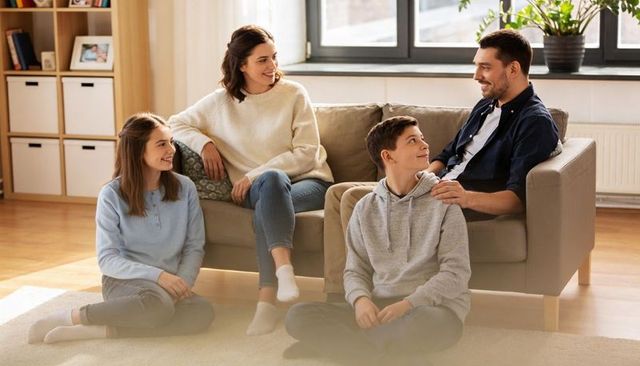 Family chatting and bonding on sofa in bright modern living room, casual home lifestyle
