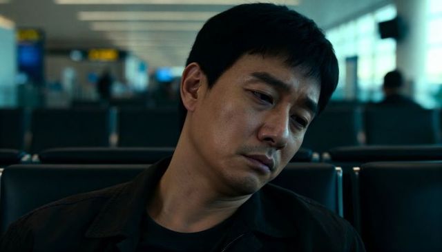 Contemplative asian traveler waiting alone in dim airport gate with cool cinematic mood