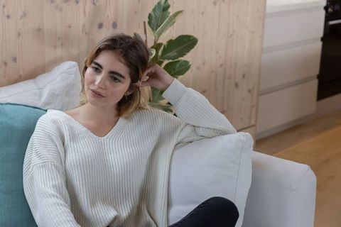 Contemplative Woman Relaxing at Home in Cozy Minimalist Living Room
