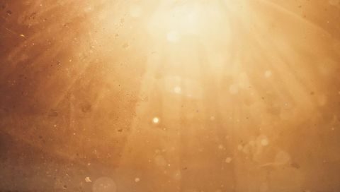 Golden sunbeams through window backlit dust motes warm glowing abstract background