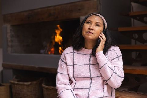 Woman in Pajamas Talking on Phone by Fireplace, Cozy and Relaxed