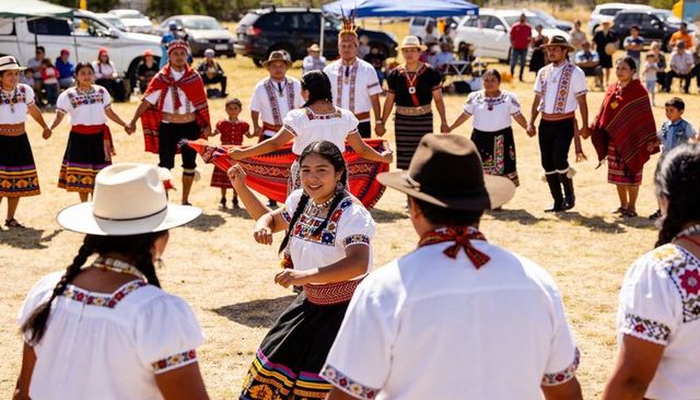 Smiling woman dancing in embroidered blouse and colorful skirt during traditional outdoor circle dan