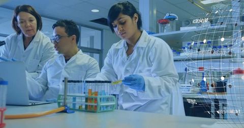 Scientists collaborating in laboratory pipetting yellow solution