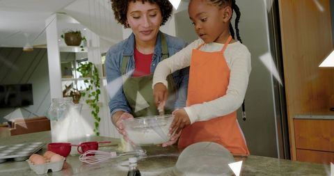 Parent and child mixing batter at kitchen counter teaching baking skills and bonding