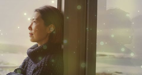 Contemplative Asian Woman Gazing Through Glow-Accented Window