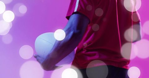 Holding volleyball at hip in magenta bokeh lighting showing strength and focus