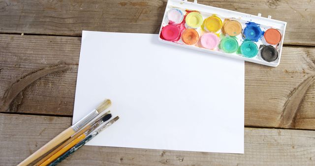 Watercolor paint and paintbrushes with canvas on wooden background - Download Free Stock Photos Pikwizard.com