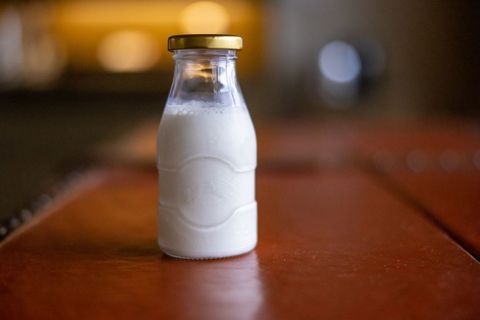 Rustic glass milk bottle on wooden table, softly lit