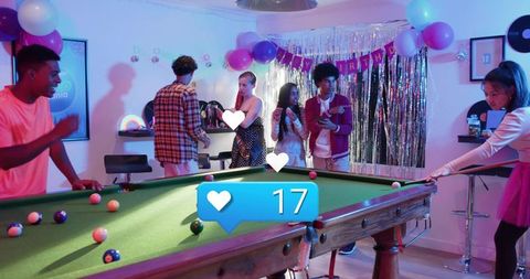 Friends playing pool celebrating birthday in colorful rec room with balloons and disco lights