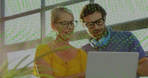 Mature colleagues collaborating on laptop with green binary overlay in bright workspace