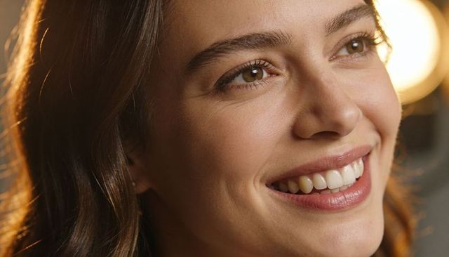 Warm studio headshot smiling woman with dimples and glowing skin natural makeup closeup