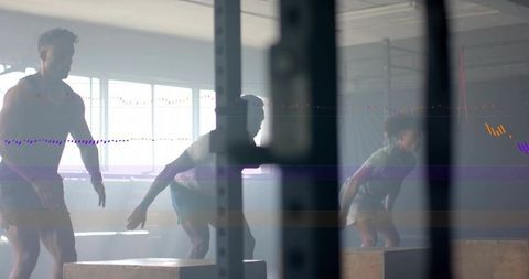 Backlit trio performing plyo box jumps in gym rig for high-intensity group training