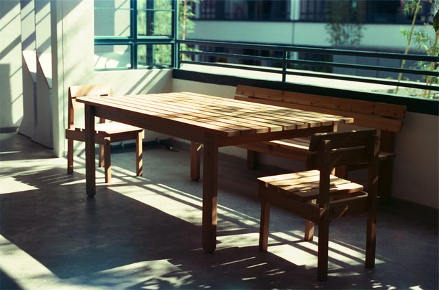Wooden table and chairs on modern balcony receiving bright sunlight. Ideal for illustrating outdoor living spaces, balconies in contemporary apartments, or promoting outdoor furniture.