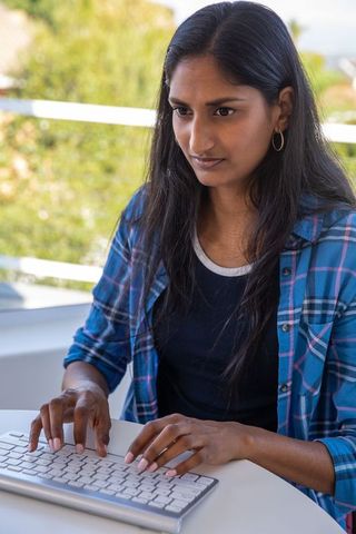 Focused Woman Typing on Balcony with Nature View