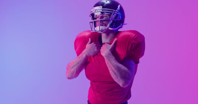 Football player poses confidently in red uniform against colorful background. Useful for sports-related articles, fitness promotions, and advertising athletic gear.