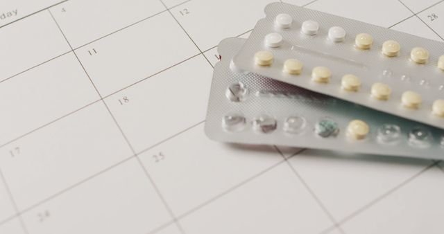 This visual focuses on birth control pills placed on top of a calendar. It signifies the intersection of healthcare and scheduling for family planning or contraceptive purposes. Ideal for medical websites, women's health articles, and educational materials about birth control.