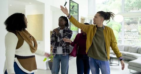 Diverse Friends Touring Modern Home, Man Gesturing Enthusiastically in Bright Living Room