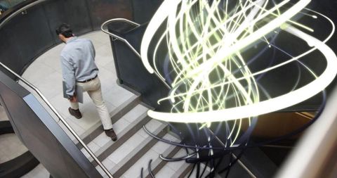 Businessman Descending Modern Spiral Staircase with Innovative Art Installations