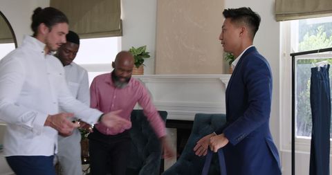 Friends helping groom prepare for wedding day