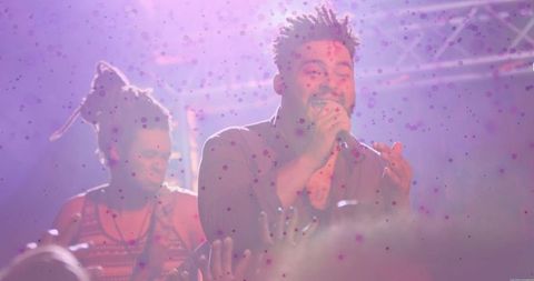 Energetic singer performing live on stage with vibrant haze