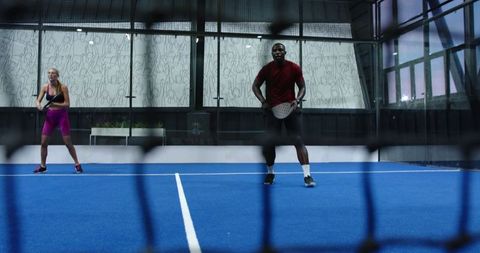 Diverse padel players engaging in doubles game on modern blue court