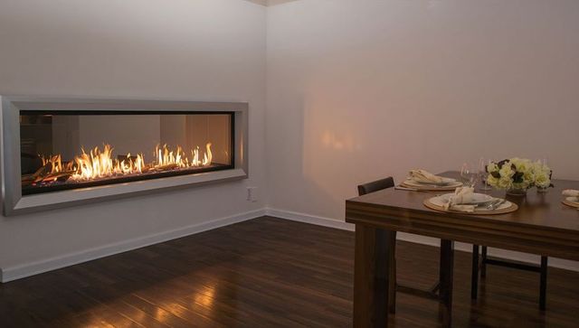Warming dining room with linear glass-front fireplace and minimalist wooden table styling