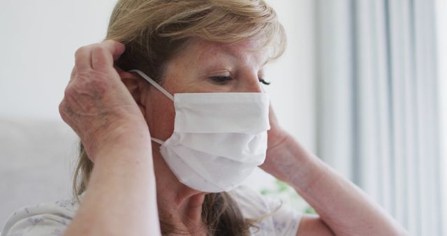 Senior Woman Wearing Face Mask Adjusting Ear Loops Indoors - Download Free Stock Images Pikwizard.com