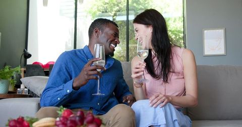 Happy Interracial Couple Toasting with Champagne on Couch