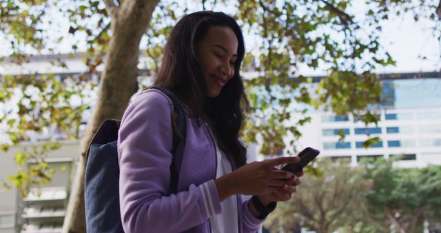 Asian woman smiling while using smartphone standing in the park. modern lifestyle and living concept