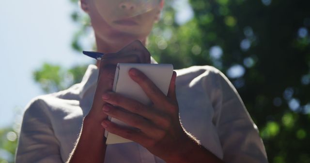 Person Writing in Notebook Outdoors on Sunny Day - Download Free Stock Images Pikwizard.com