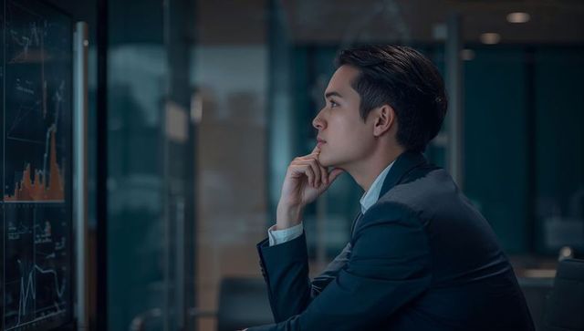 Businessman analyzing stock charts on screen, pondering data-driven investment strategy
