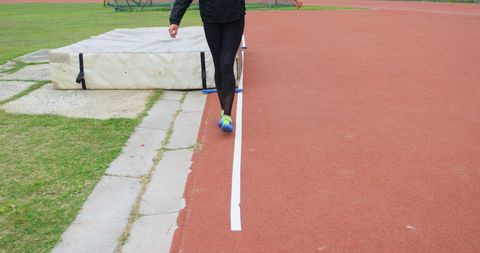 Athlete Measuring High Jump Field on Track