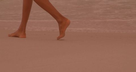 Woman Walking Barefoot on Sandy Beach in Tranquil Setting